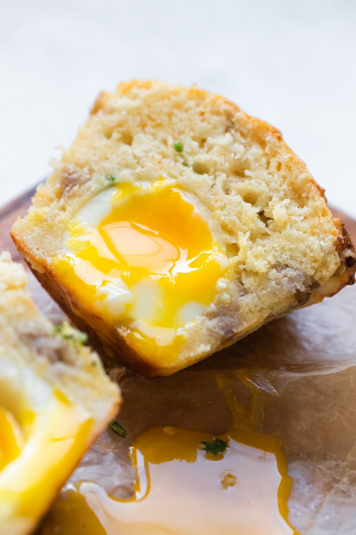 a soft boiled egg inside of a breakfast muffin cut in half on a cutting board