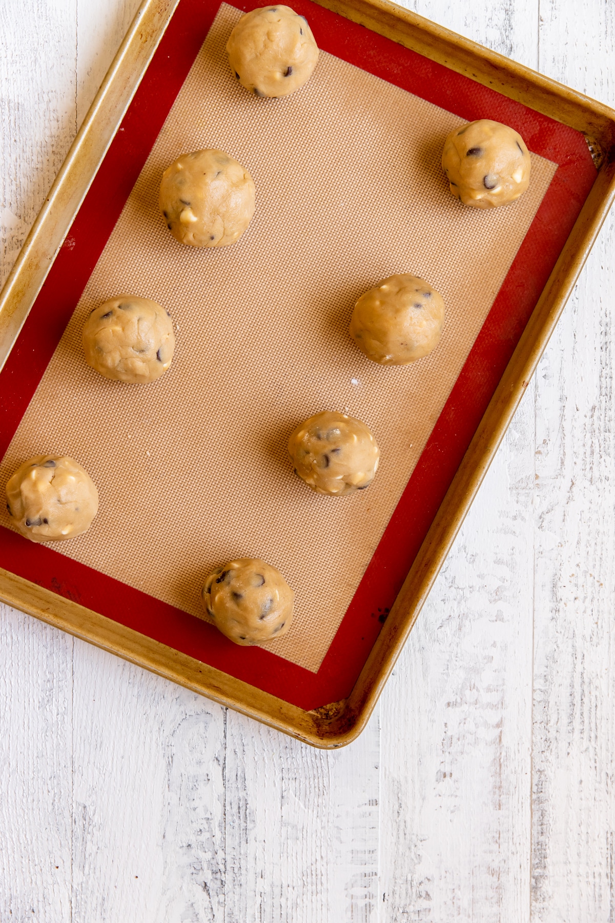 cookie dough balls on a silicone lined baking sheet. 