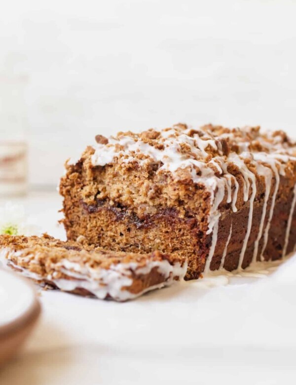 a slice cut off from a loaf of banana bread with icing drizzled on top.