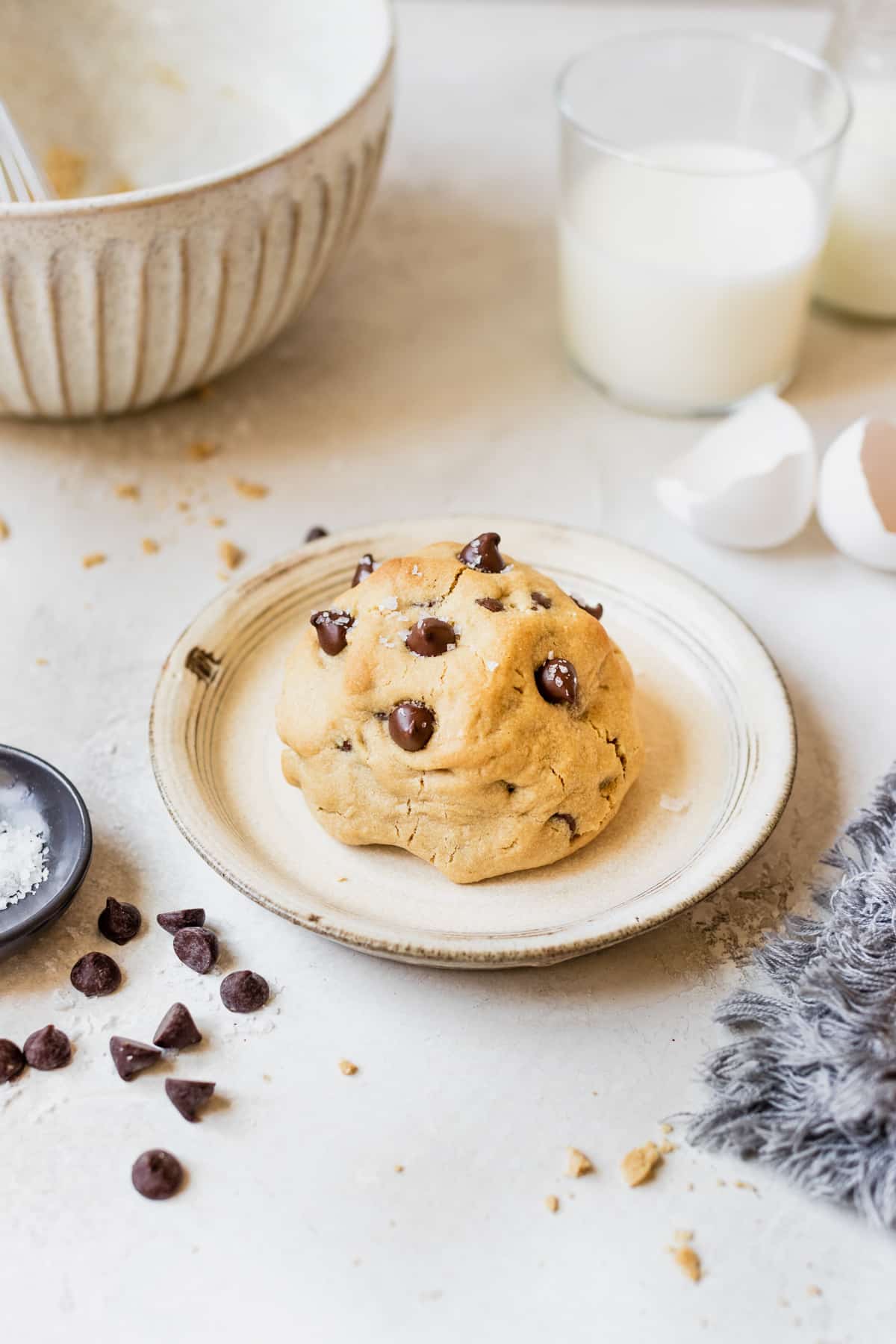 a chocolate chip cookie on a plate topped with sea salt.