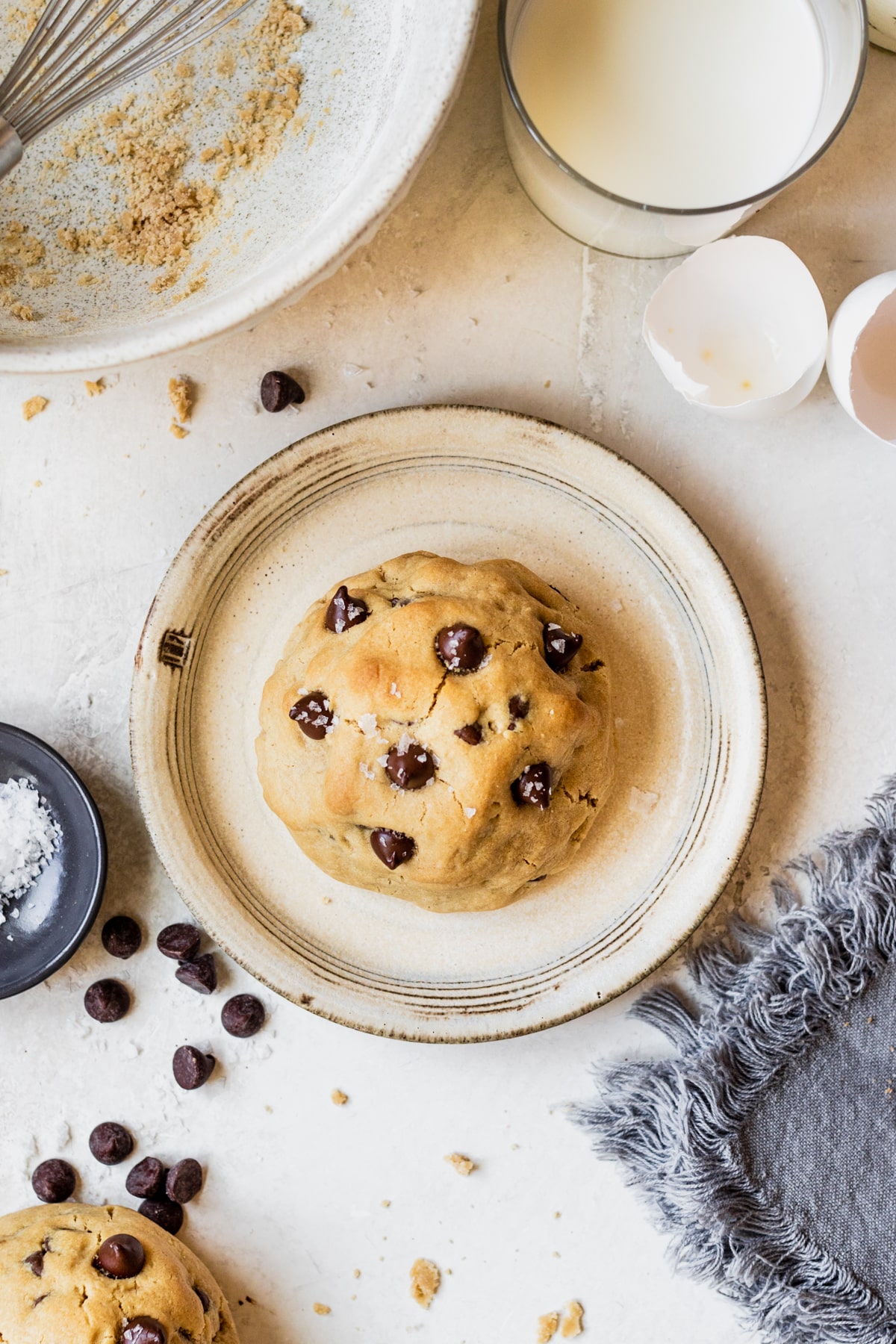 a chocolate chip cookie on a plate topped with sea salt.