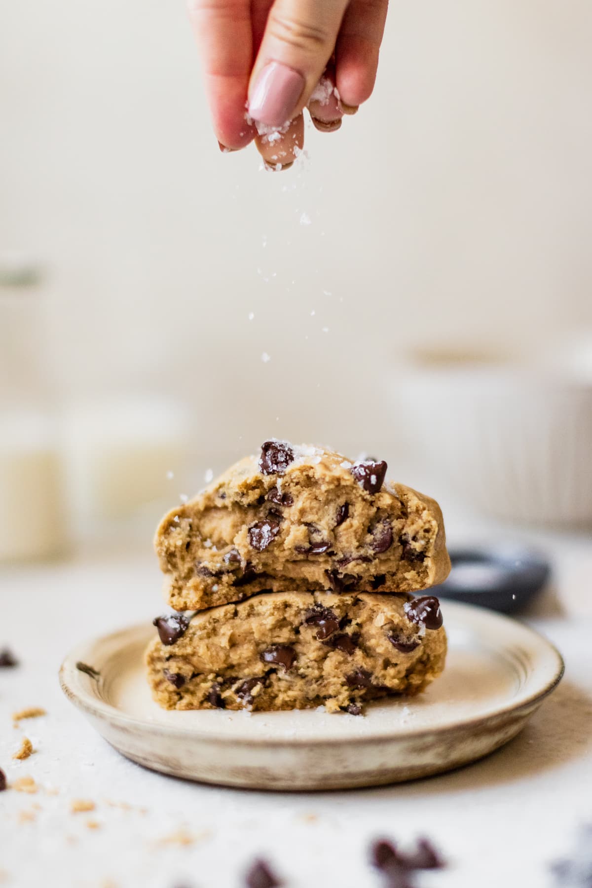 a chocolate chip cookie on a plate topped with sea salt.