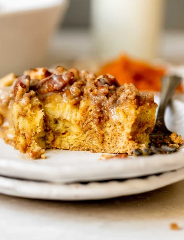 french toast made with pumpkin on a white plate topped with a brown sugar pecan streusel and maple glaze.