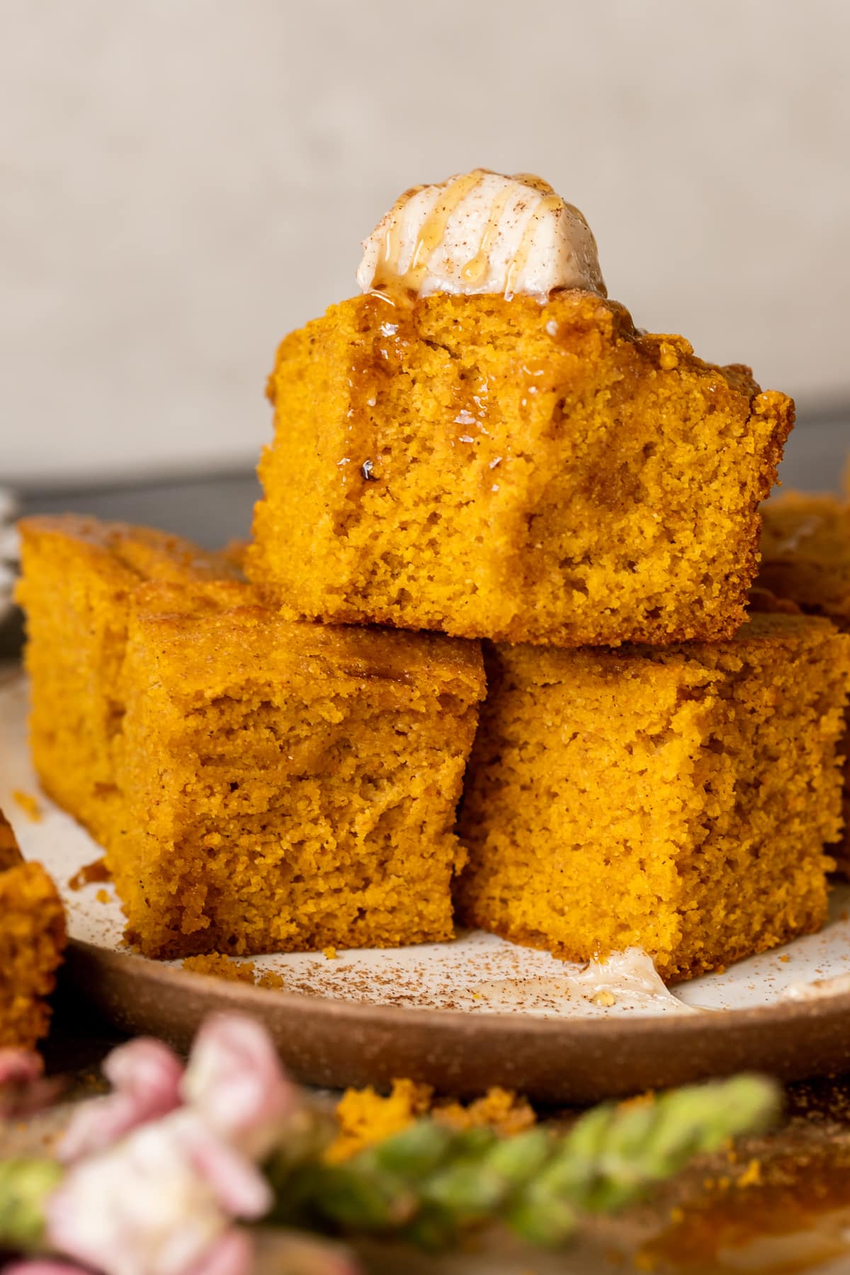 cornbread on a plate topped with whipped butter and honey and pumpkin pie spice.