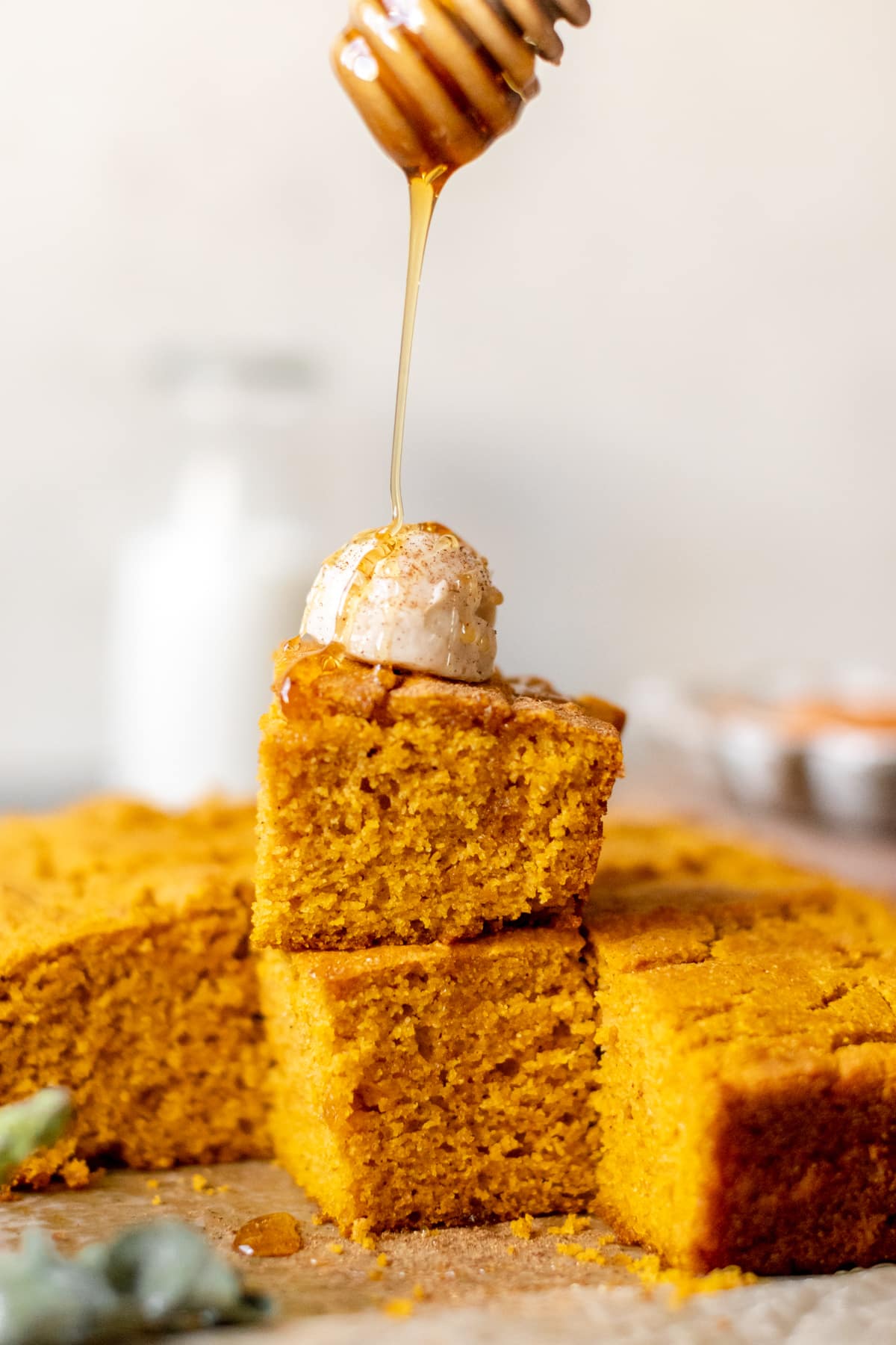 cornbread on a plate topped with whipped butter and honey and pumpkin pie spice.