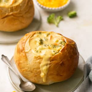 soup in a bread bowl with a spoon on the side.