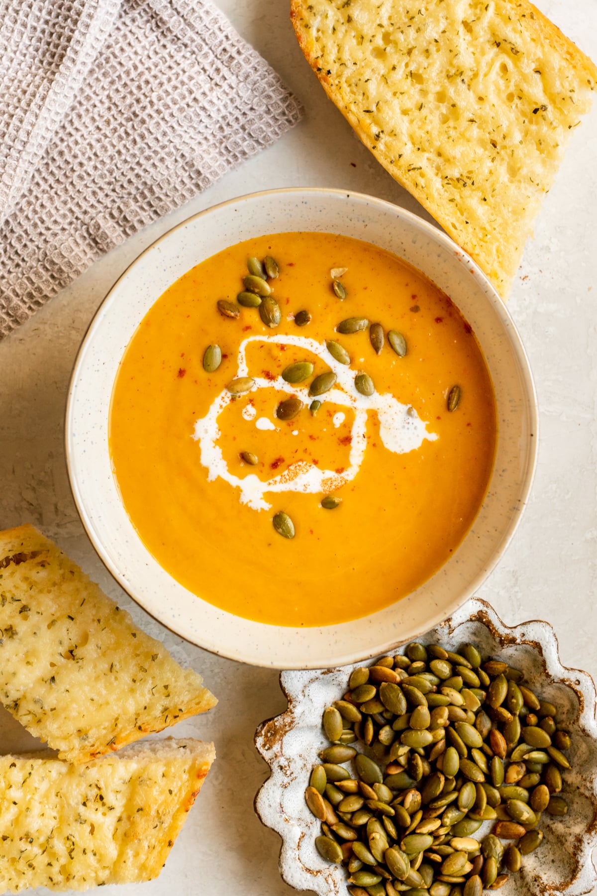 squash soup in a bowl topped with pepitas, cream, and paprika.