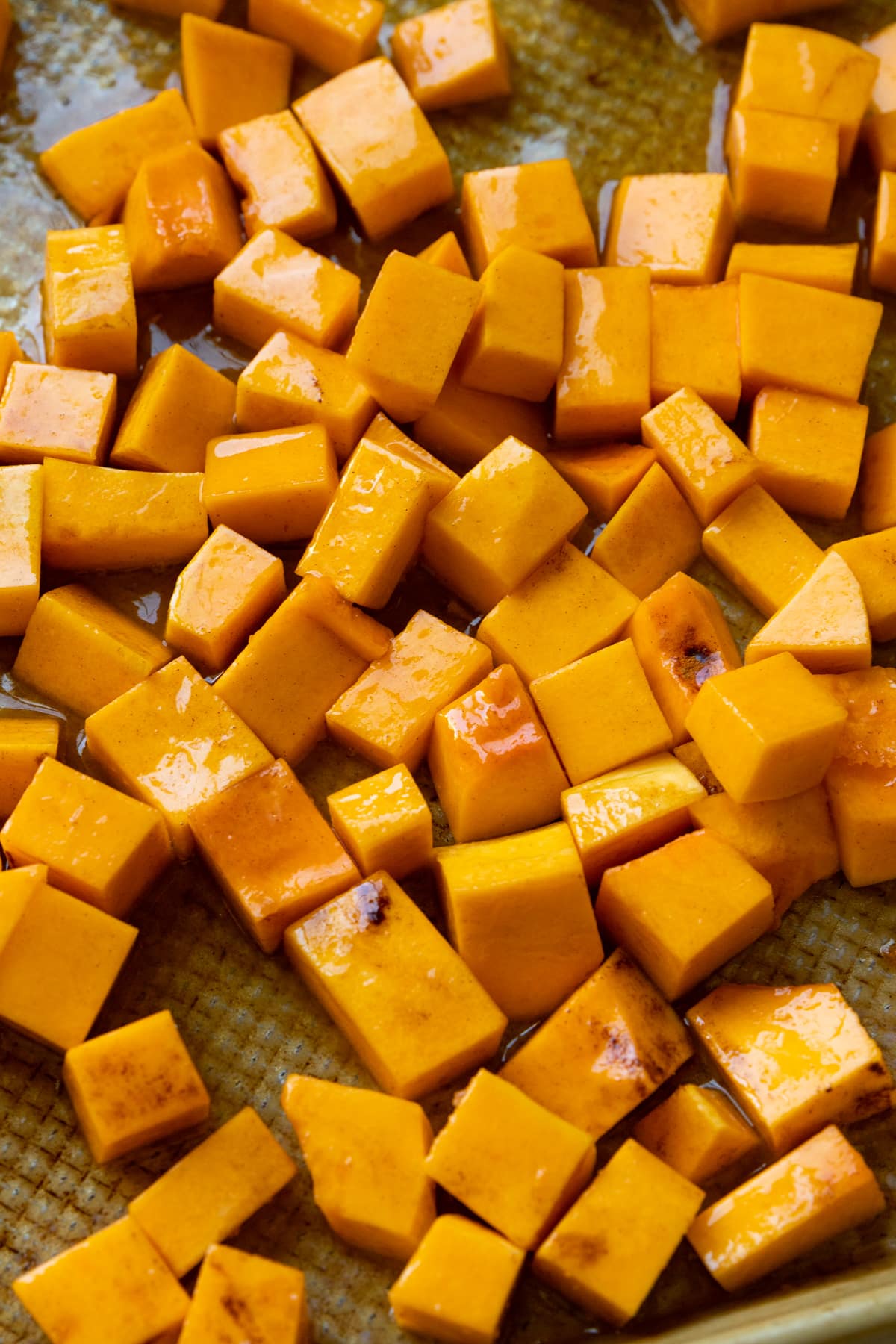 butternut squash on a baking sheet tossed in honey and butter and cinnamon. 