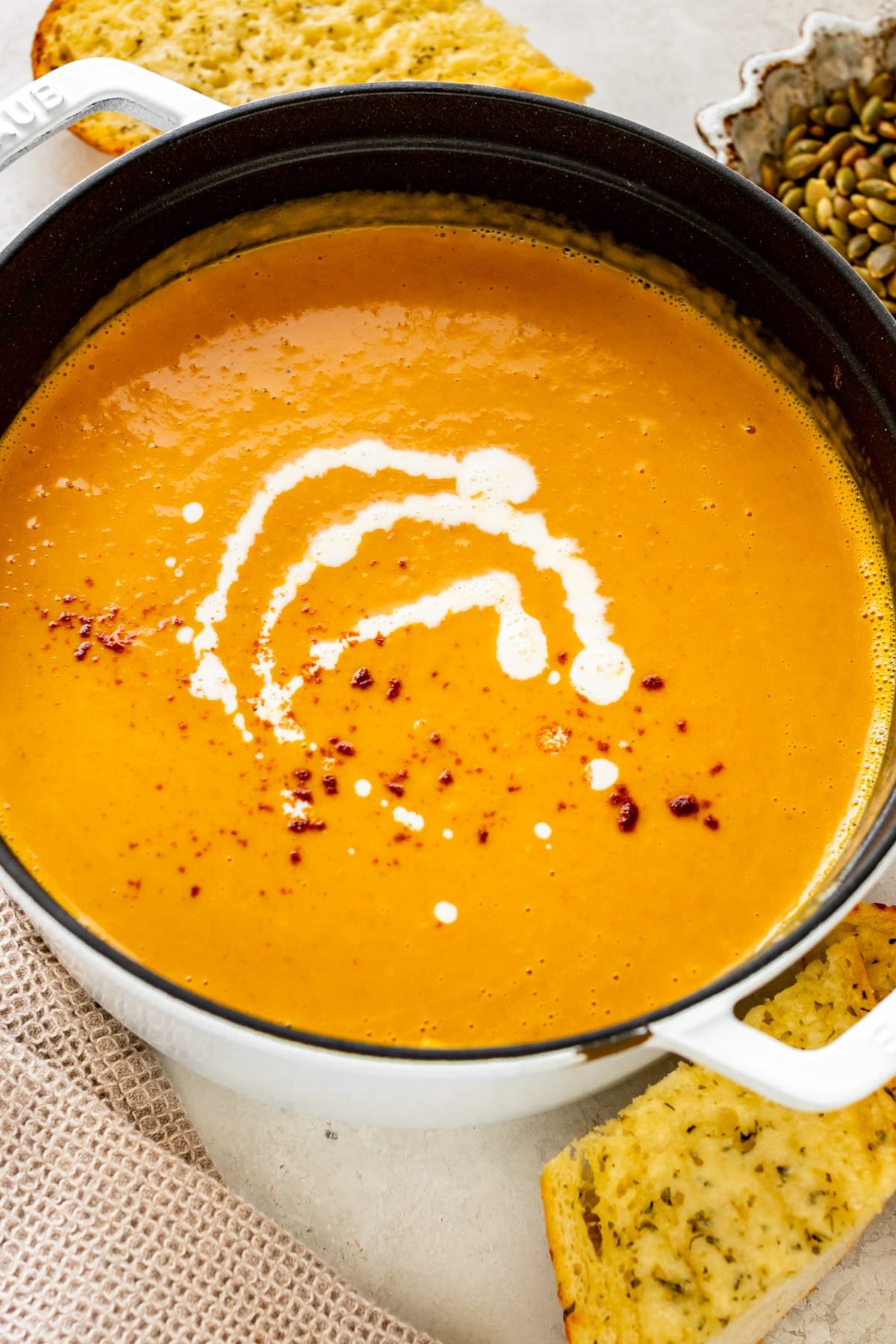squash soup in a dutch over topped with cream and paprika.