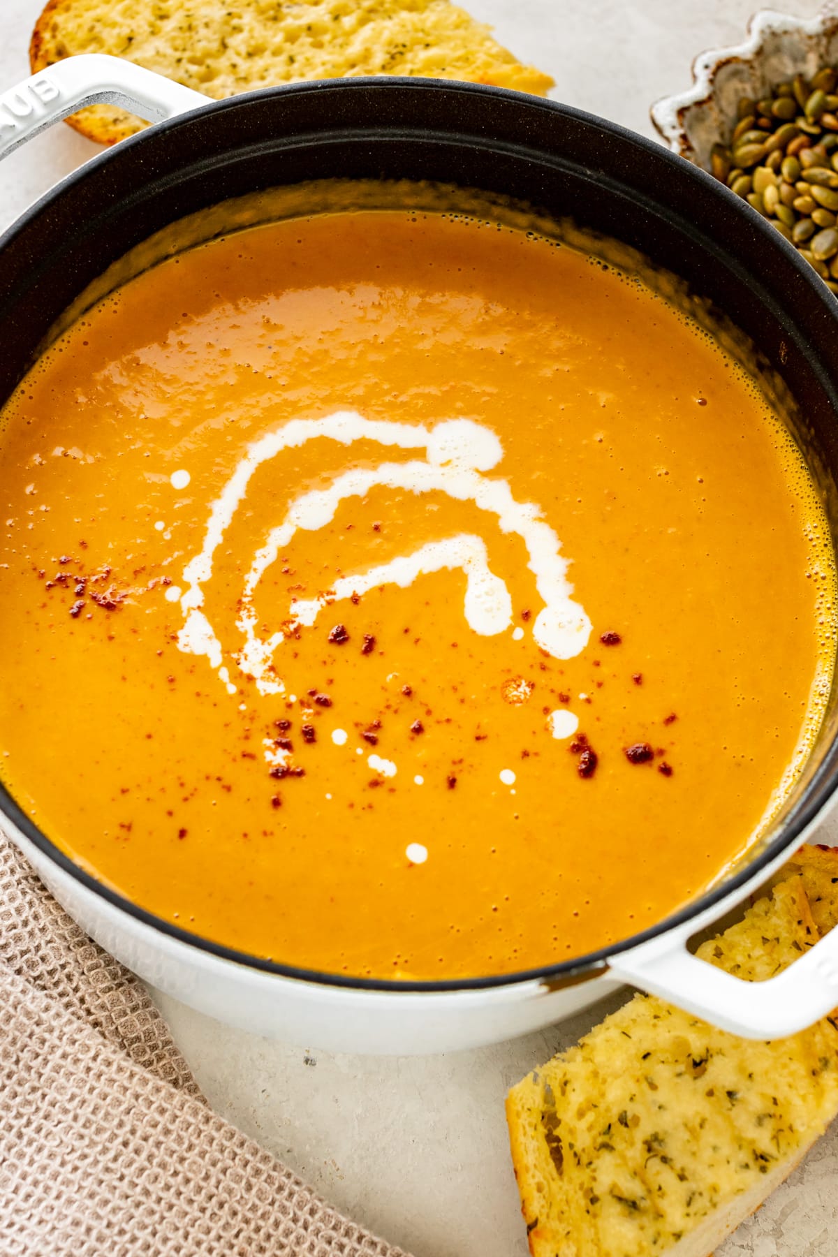 squash soup in a dutch over topped with cream and paprika.