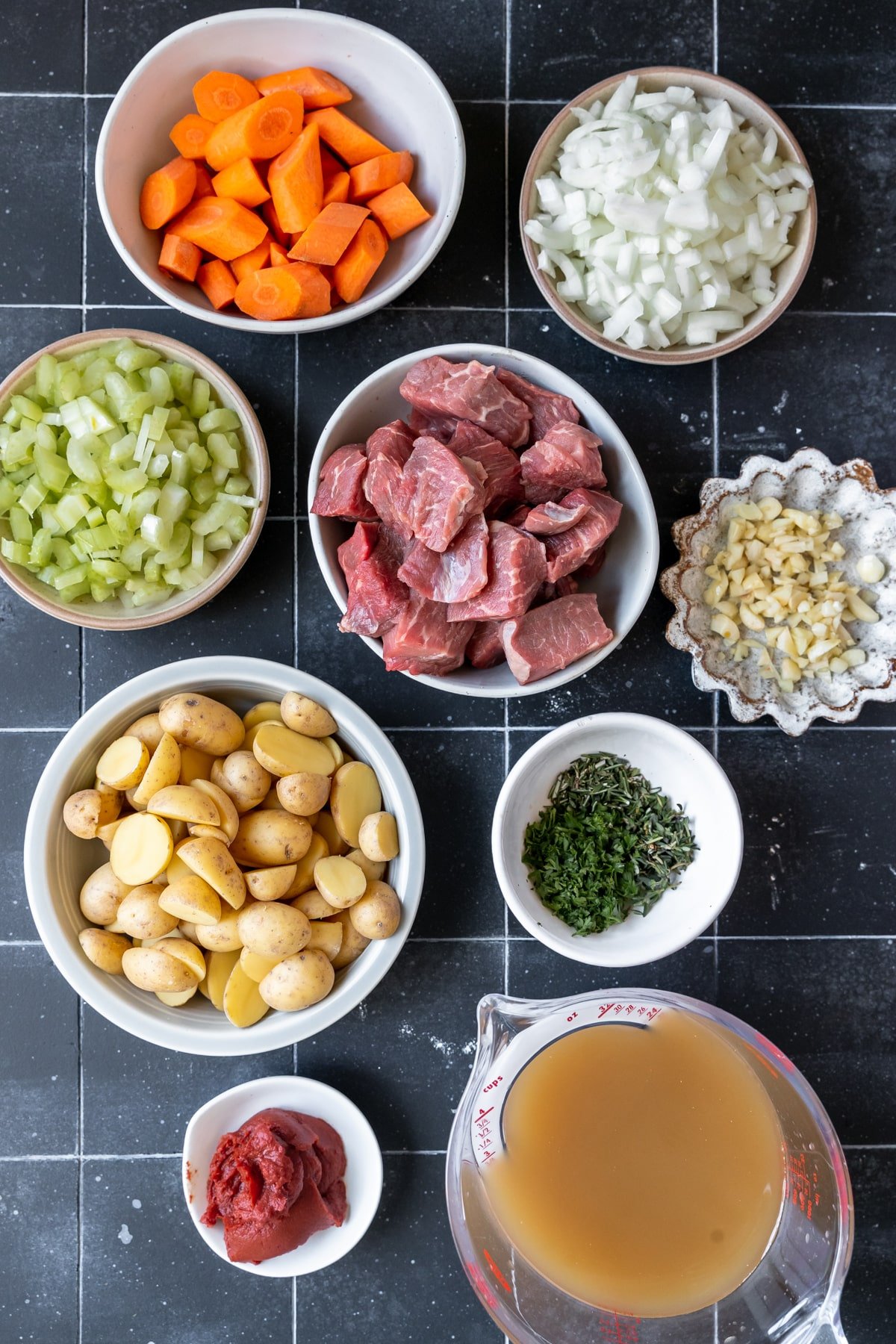 ingredients in small white glass bowls chopped up to make a stew. 