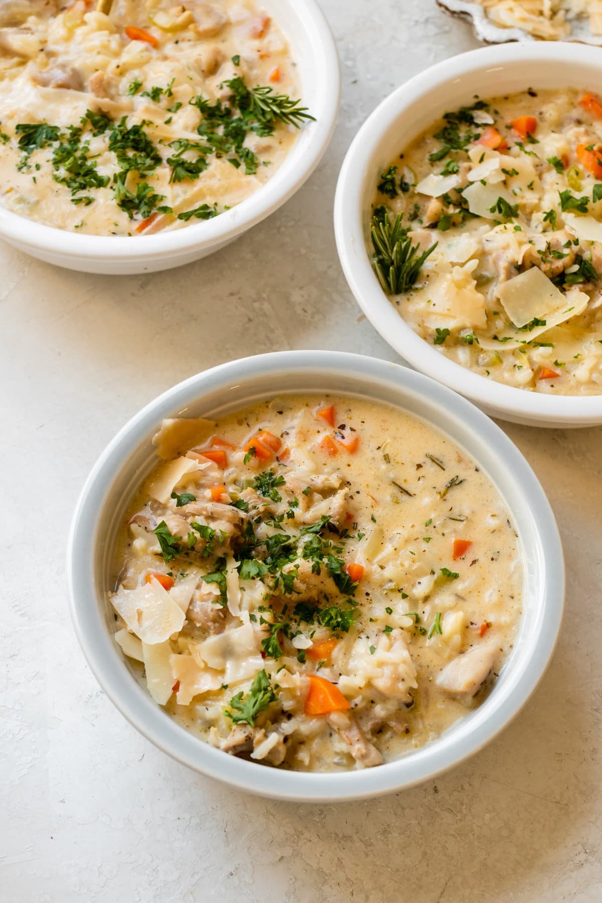 chicken rice soup in a bowls garnished with parmesan cheese, black pepper and fresh parsley. 