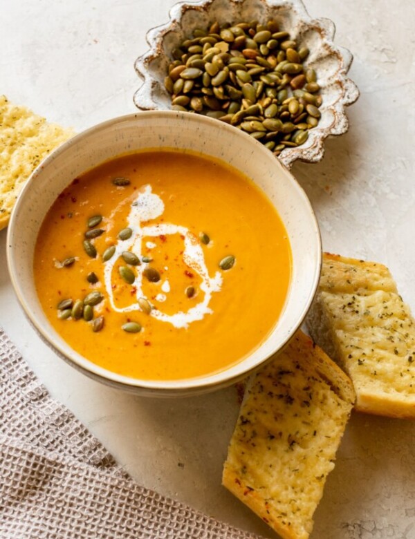 squash soup in a bowl topped with pepitas, cream, and paprika.