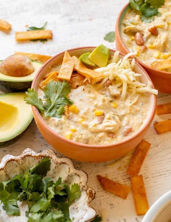 enchilada soup in a bowl garnished with cilantro, tortilla strips, avocado and Monterey Jack cheese.