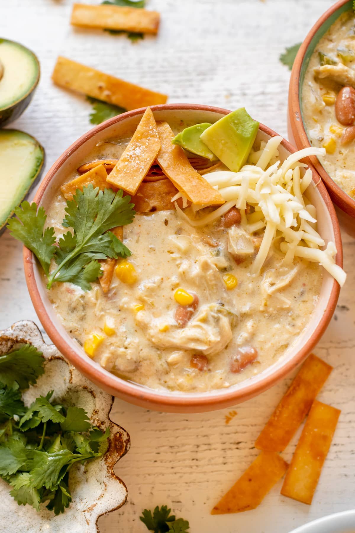 enchilada soup in a bowl garnished with cilantro, tortilla strips, avocado and Monterey Jack cheese.