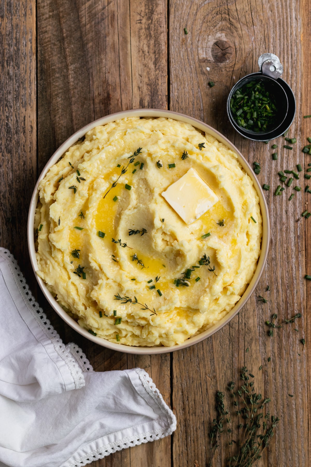 potatoes in a bowl garnished with butter, thyme and chives. 