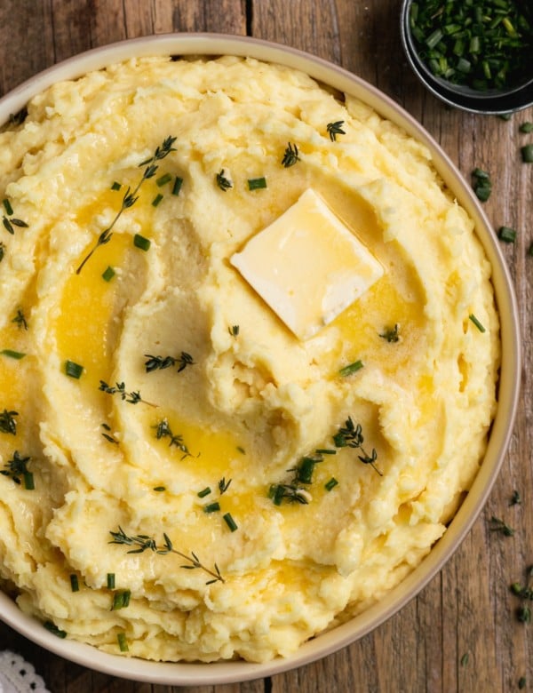 bowl of mashed potatoes with chopped chives and a pat of butter