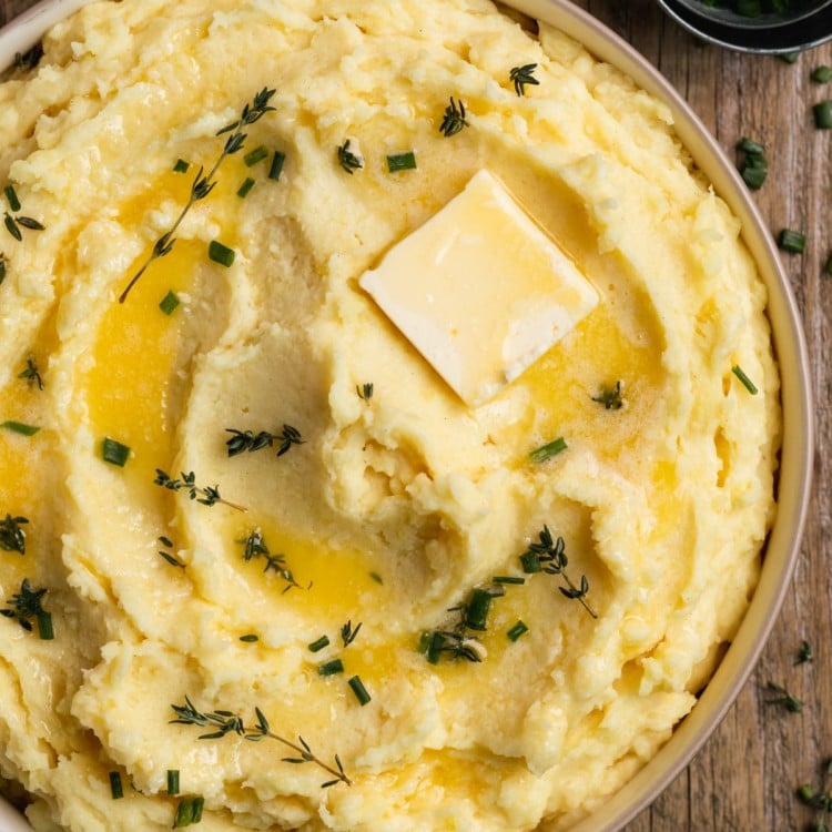 bowl of mashed potatoes with chopped chives and a pat of butter