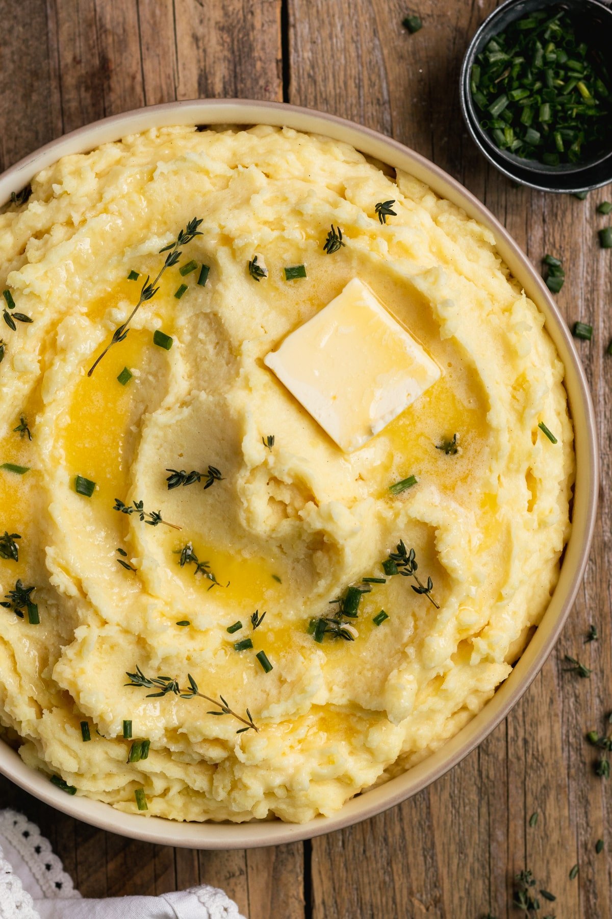 bowl of mashed potatoes with chopped chives and a pat of butter