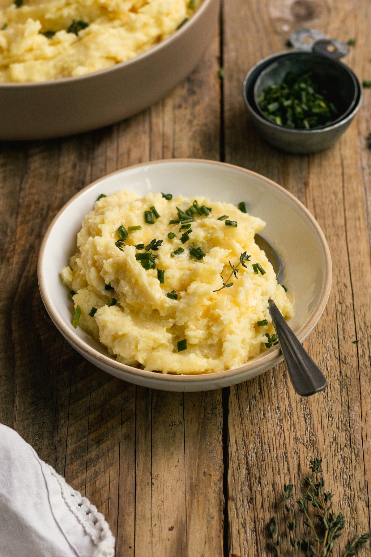 potatoes in a bowl garnished with butter, thyme and chives. 