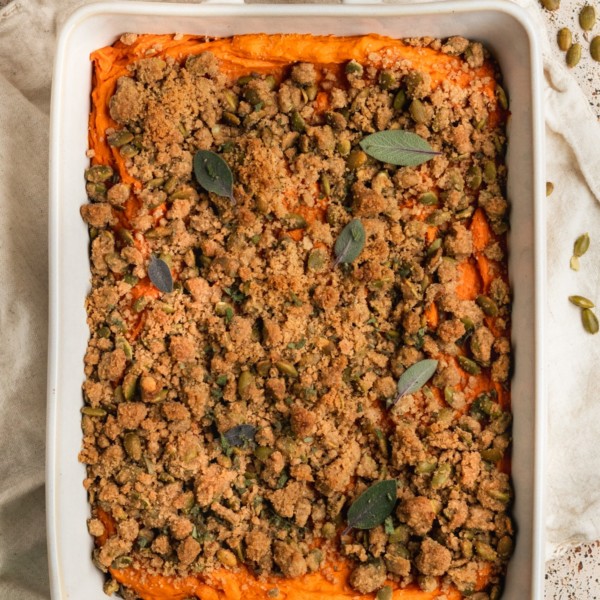 white casserole dish with mashed sweet potatoes & a crumbly topping