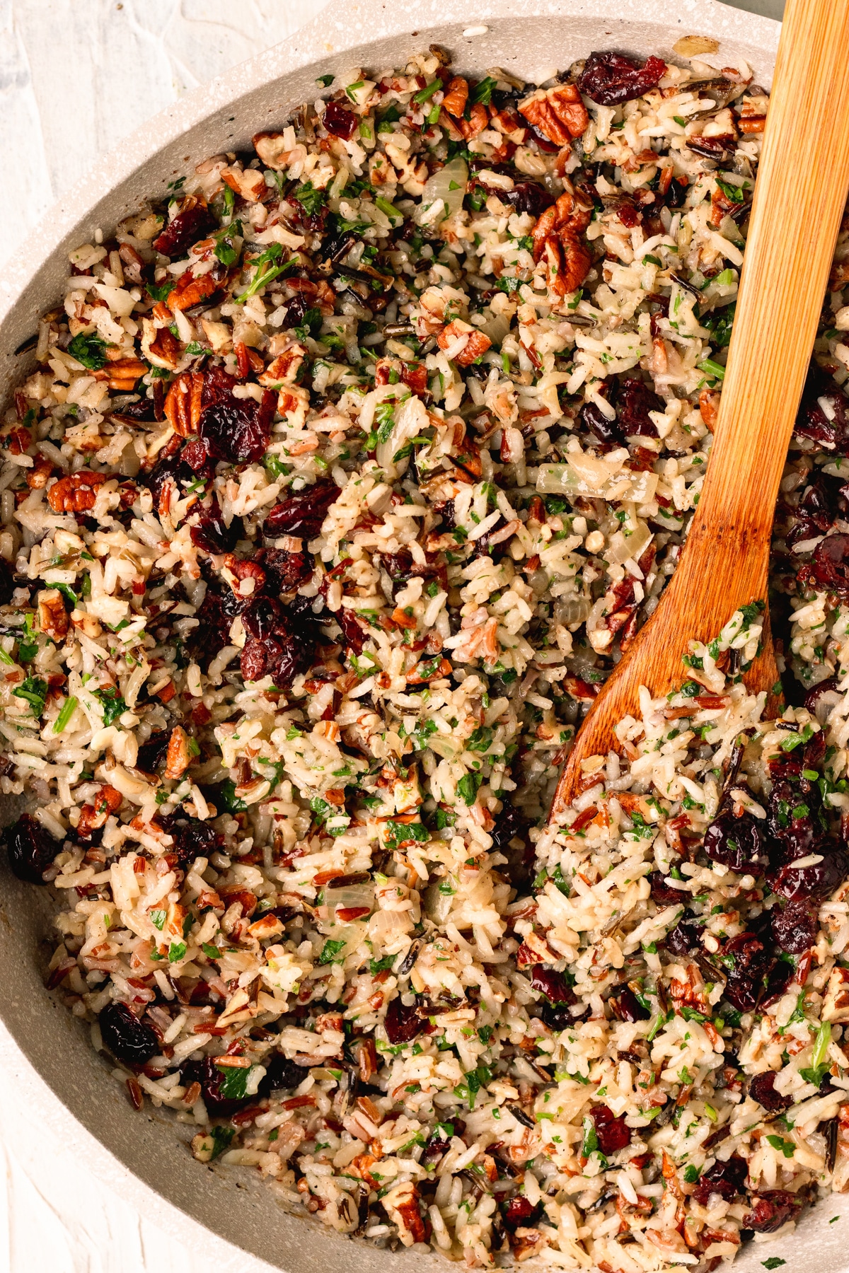 rice in a skillet with a wooden spoon garnished with parsley. 