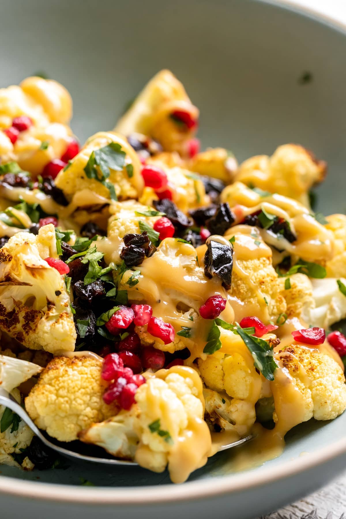 cauliflower in a blue bowl garnished with parsley and pomegranates. 