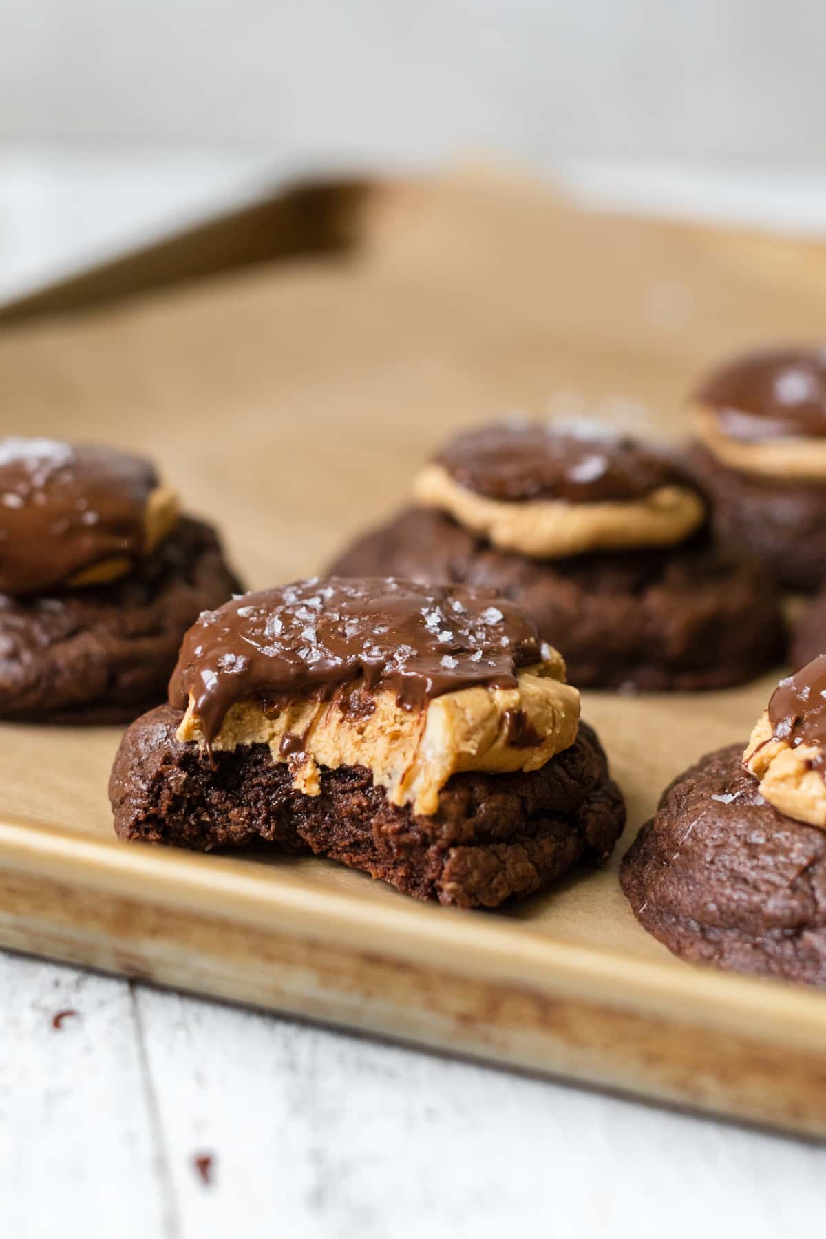 cookies on a baking sheet topped with peanut butter and chocolate with a bite take out of the cookie.