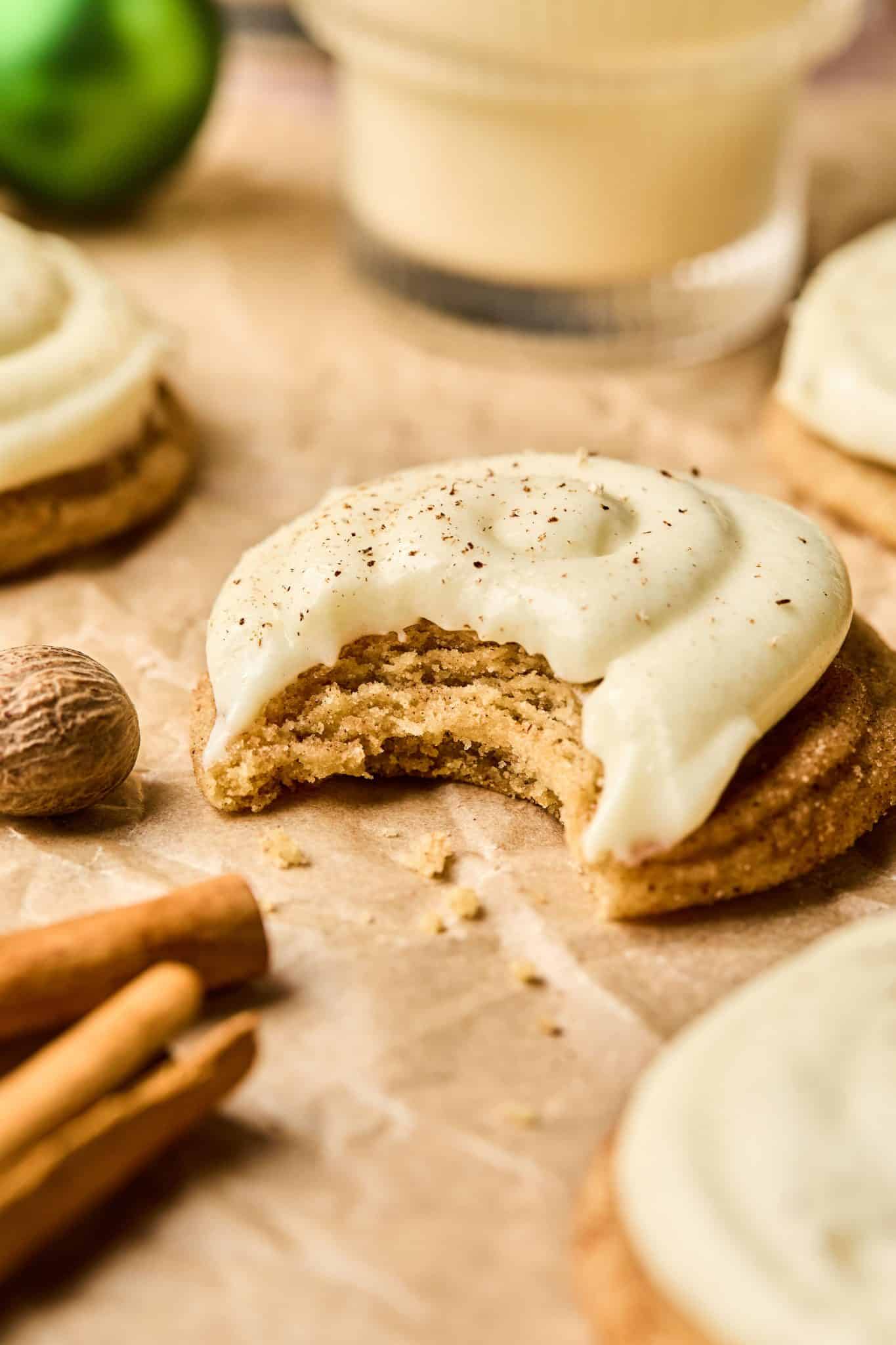 Close up of an eggnog cookie topped with cream cheese frosting and a bite taken out.