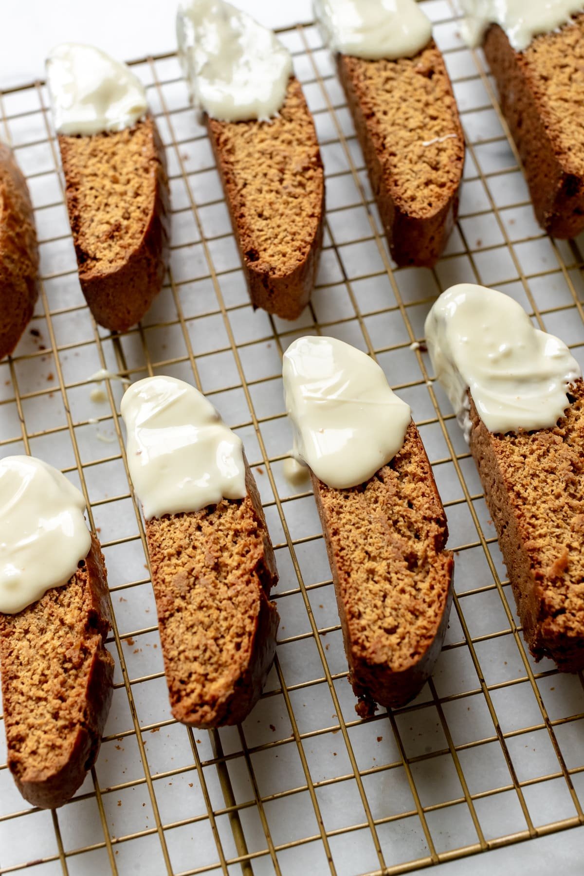 biscotti dipped in white chocolate on a wire cooling rack. 