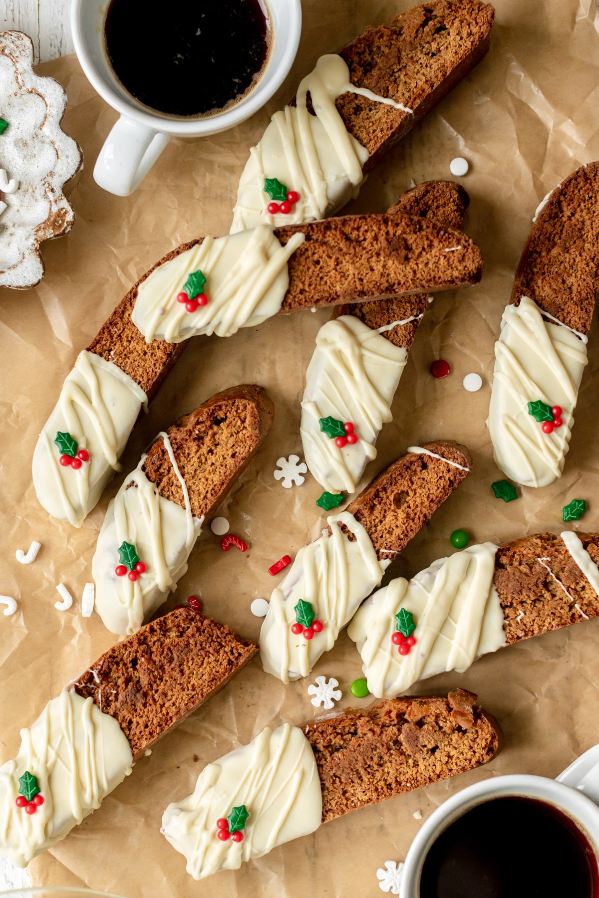 biscotti dipped in white chocolate on parchment paper with holiday sprinkles. 
