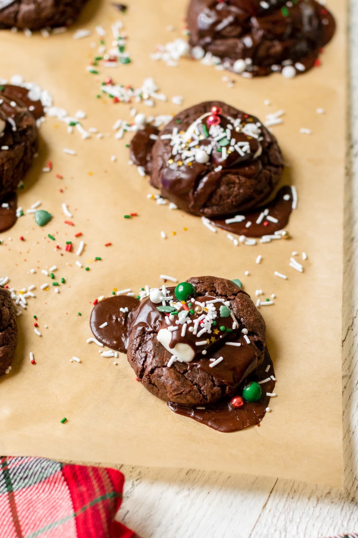 cookies on parchment paper with chocolate and sprinkles on top.
