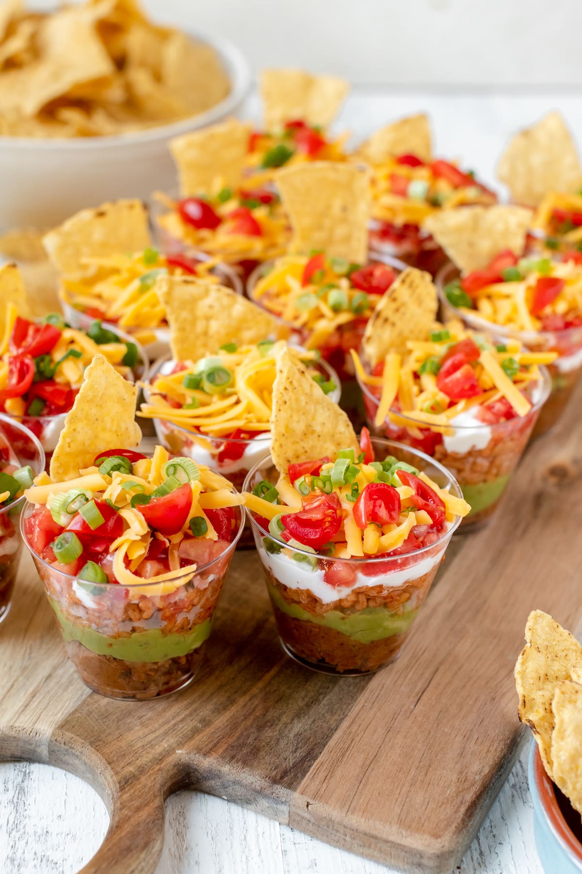 bean dip in individual plastic cups garnished with green onions and cheese. 