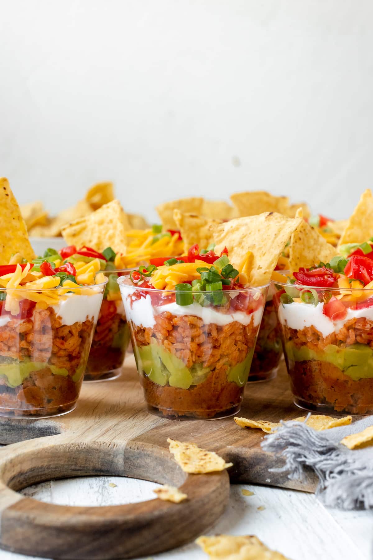 bean dip in individual plastic cups garnished with green onions and cheese. 
