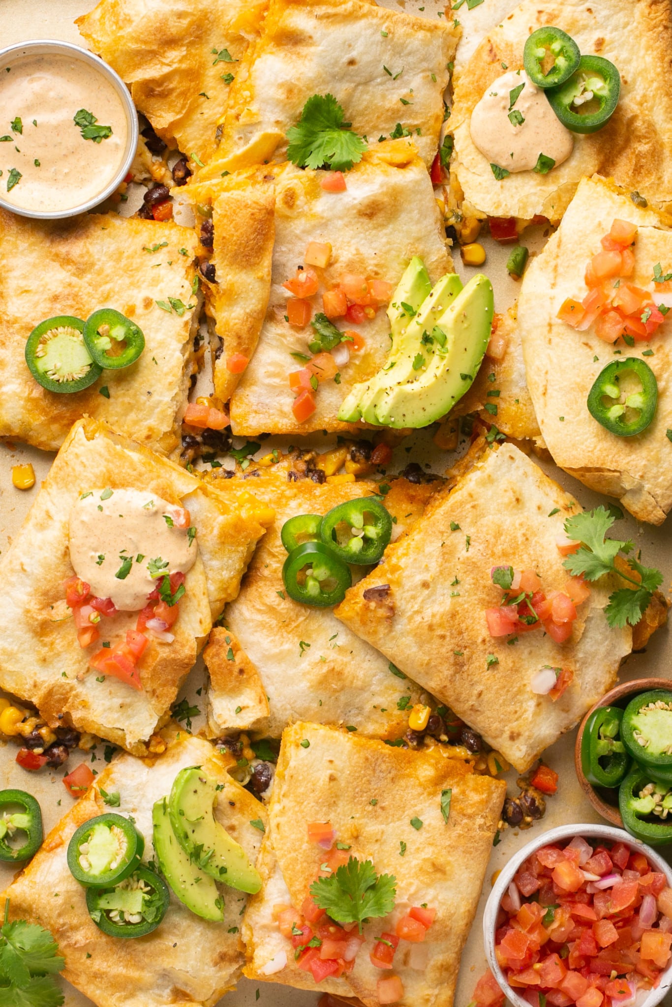 quesadillas on a sheet pan with jalapenos and avocado garnished on top.