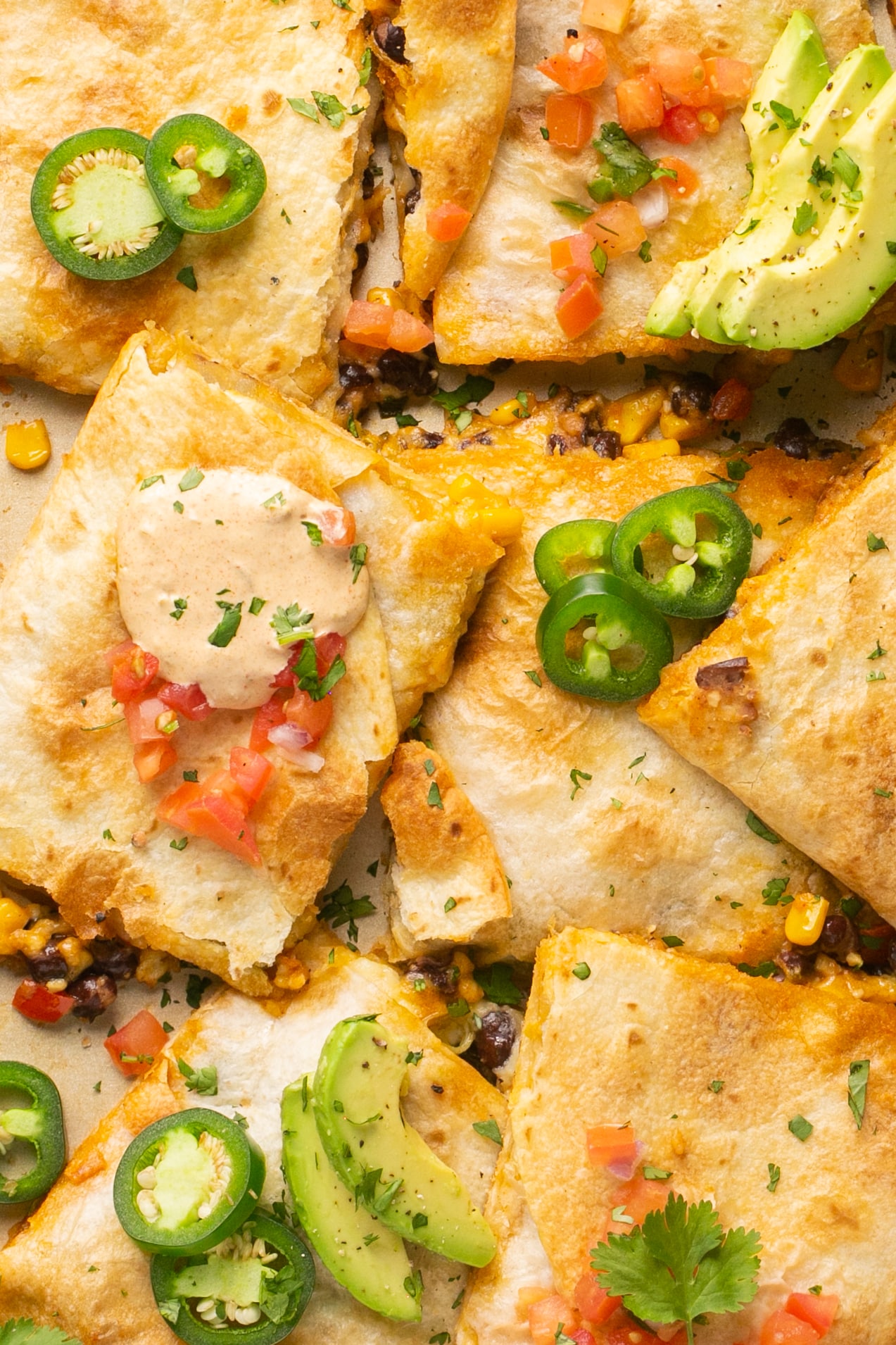 quesadillas on a sheet pan with jalapenos and avocado garnished on top.