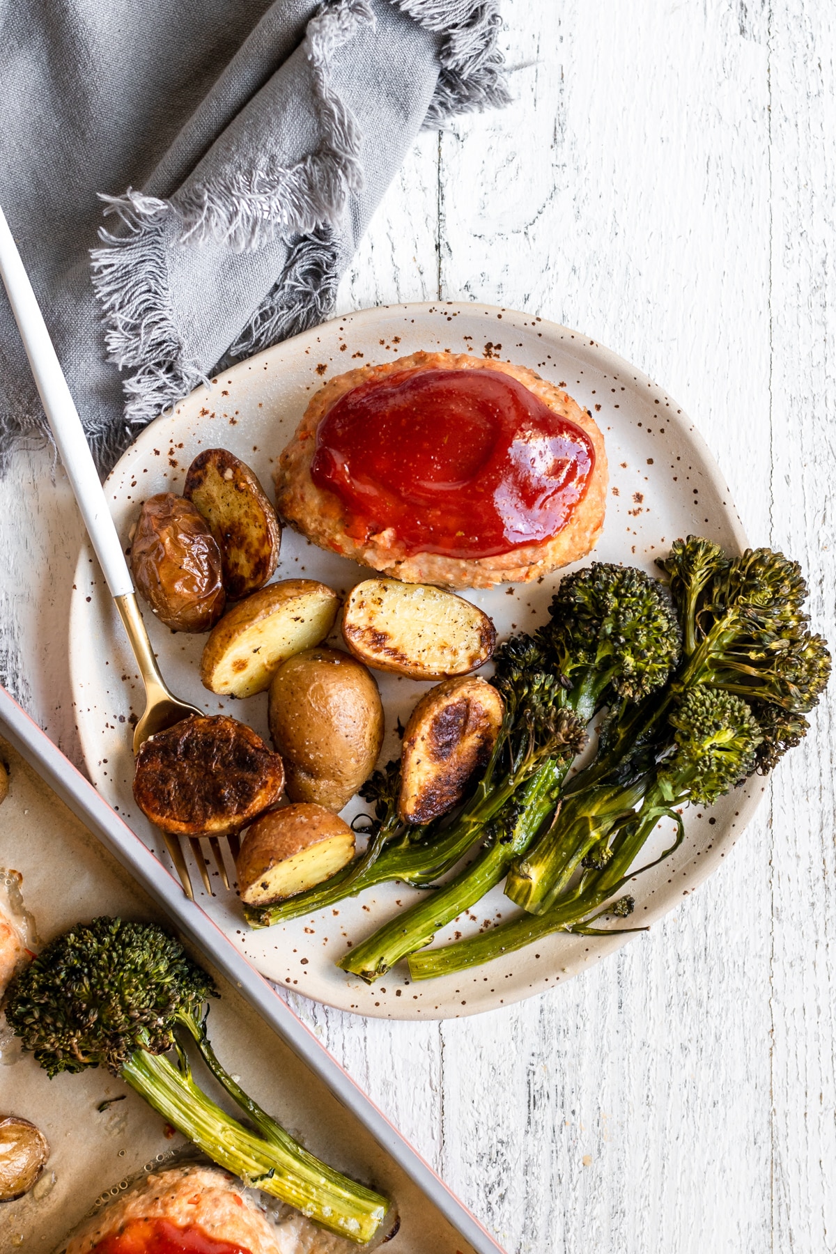 a plate with potatoes, broccolini and meatloaf. 