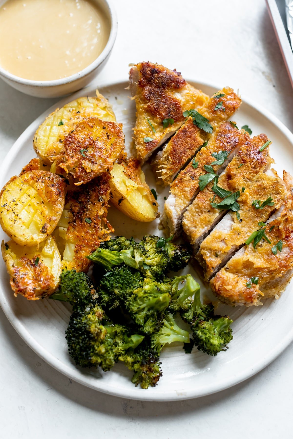 pork chop, broccoli and potatoes on a white plate. 