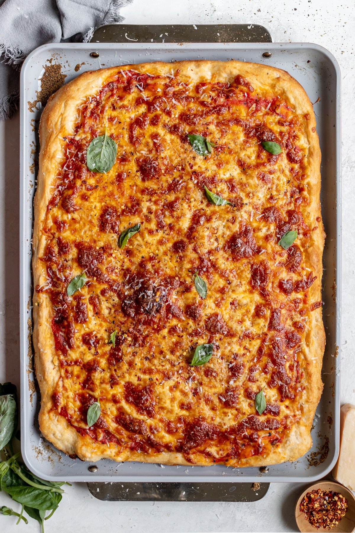 a pizza on a sheet pan garnished with fresh basil. 