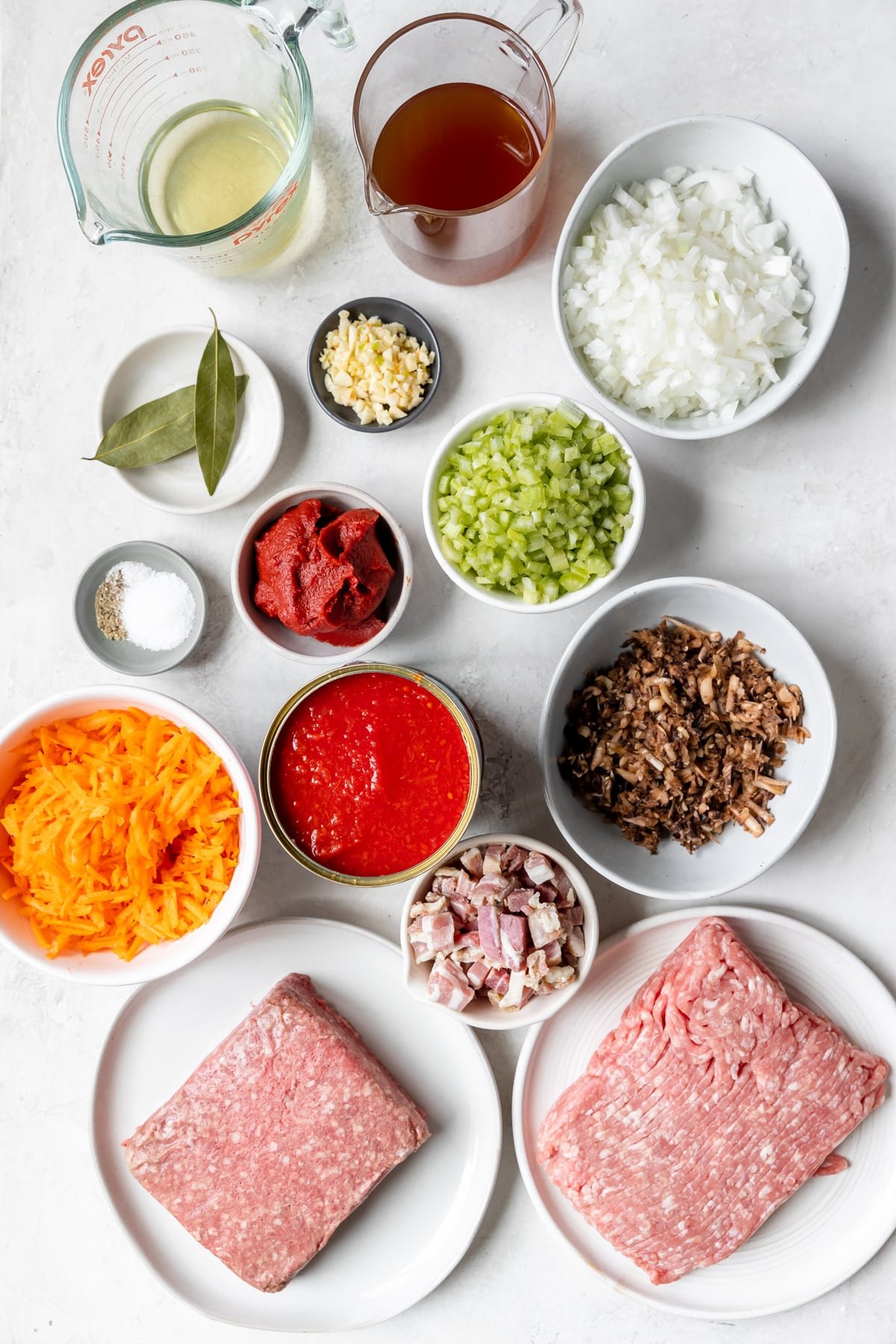 ingredients to make a meat sauce in small white bowls. 