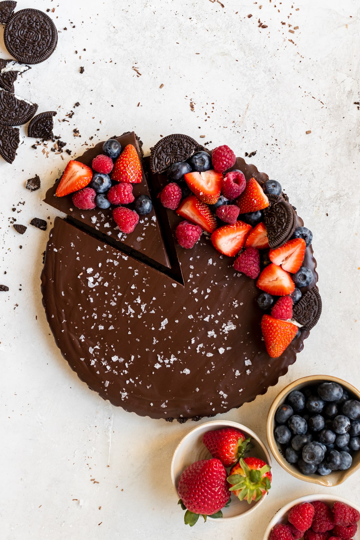 chocolate tart with one slice cut out, topped with berries and sea salt.