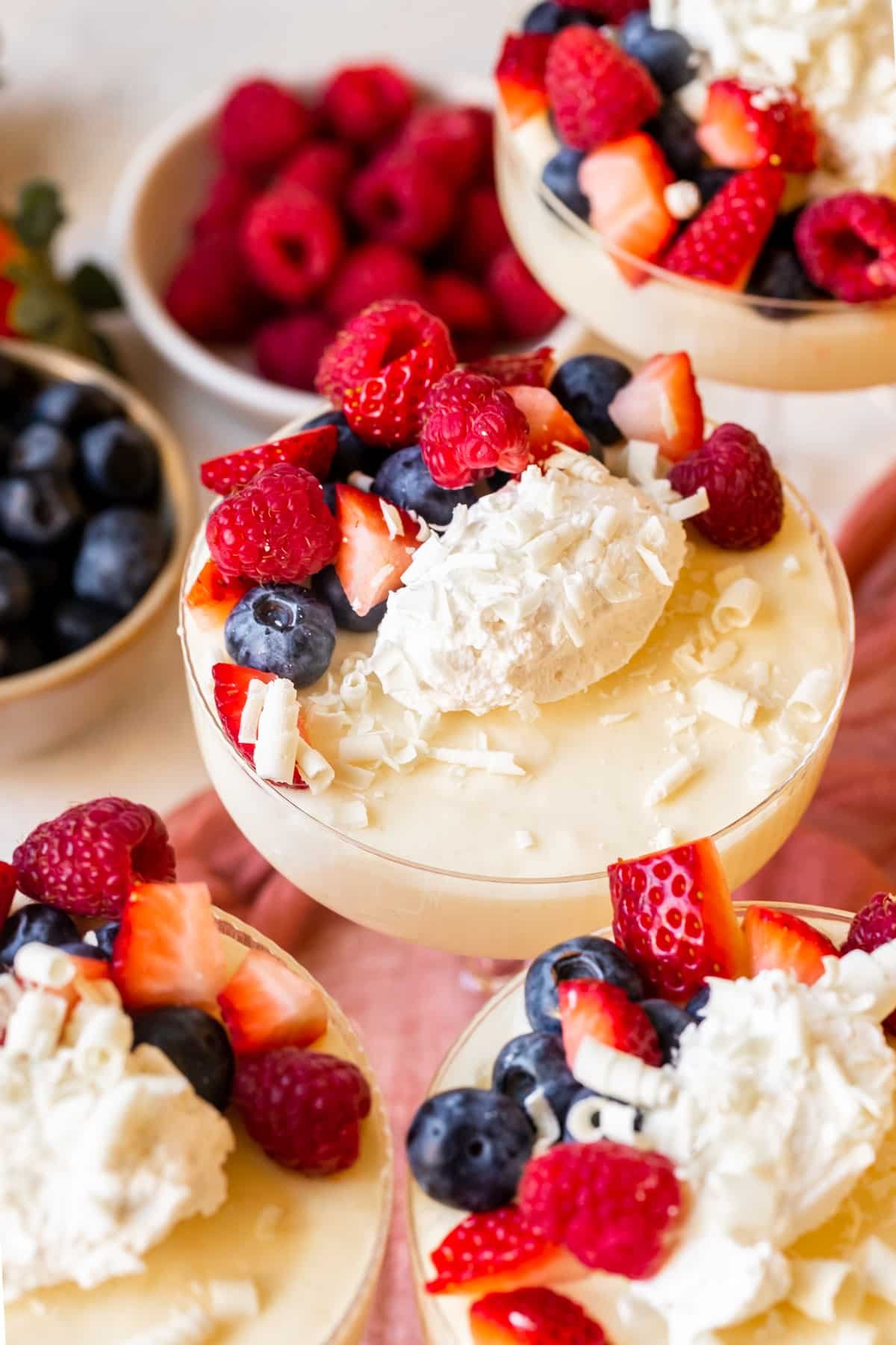 vintage martini glass full of white chocolate mousse topped with berries and white chocoalte shavings.