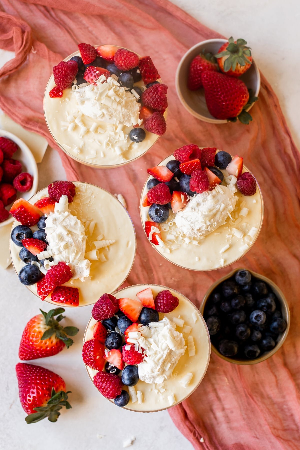 mousse in a martini glass with a bite taken out of it topped with whipped cream and fresh berries and white chocolate shavings. 