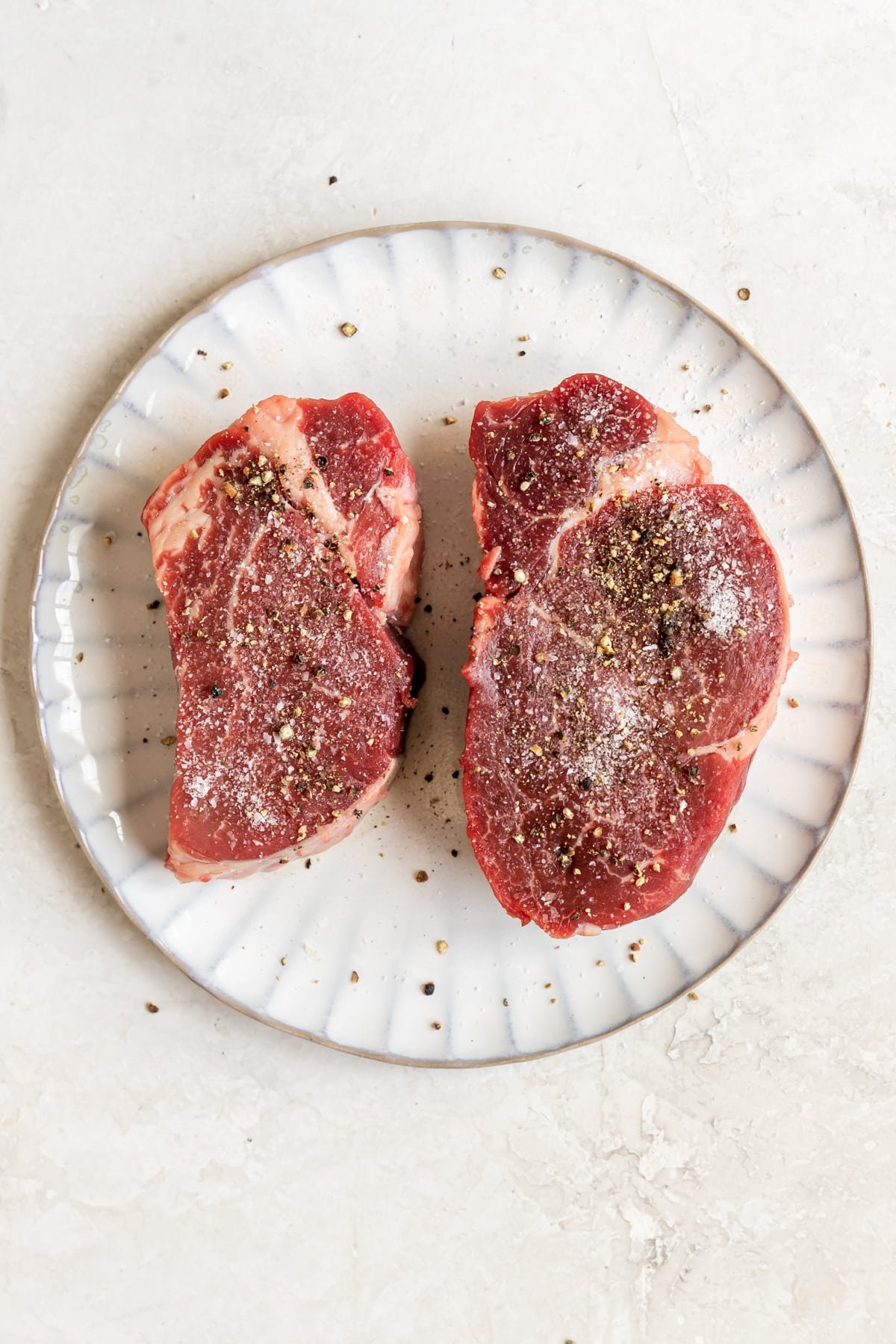 steak on a plate seasoned with salt and pepper.