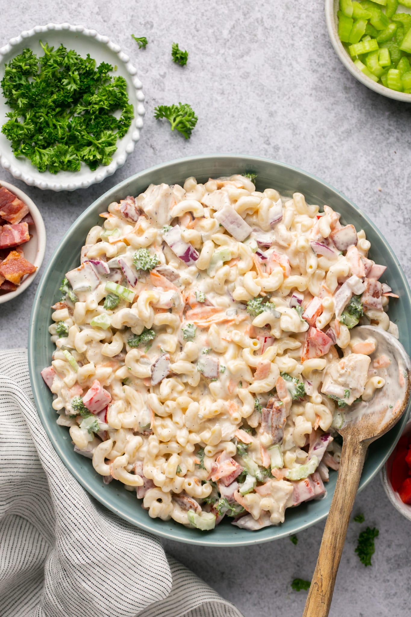 macaroni salad in a blue bowl with a wooden serving spoon. 