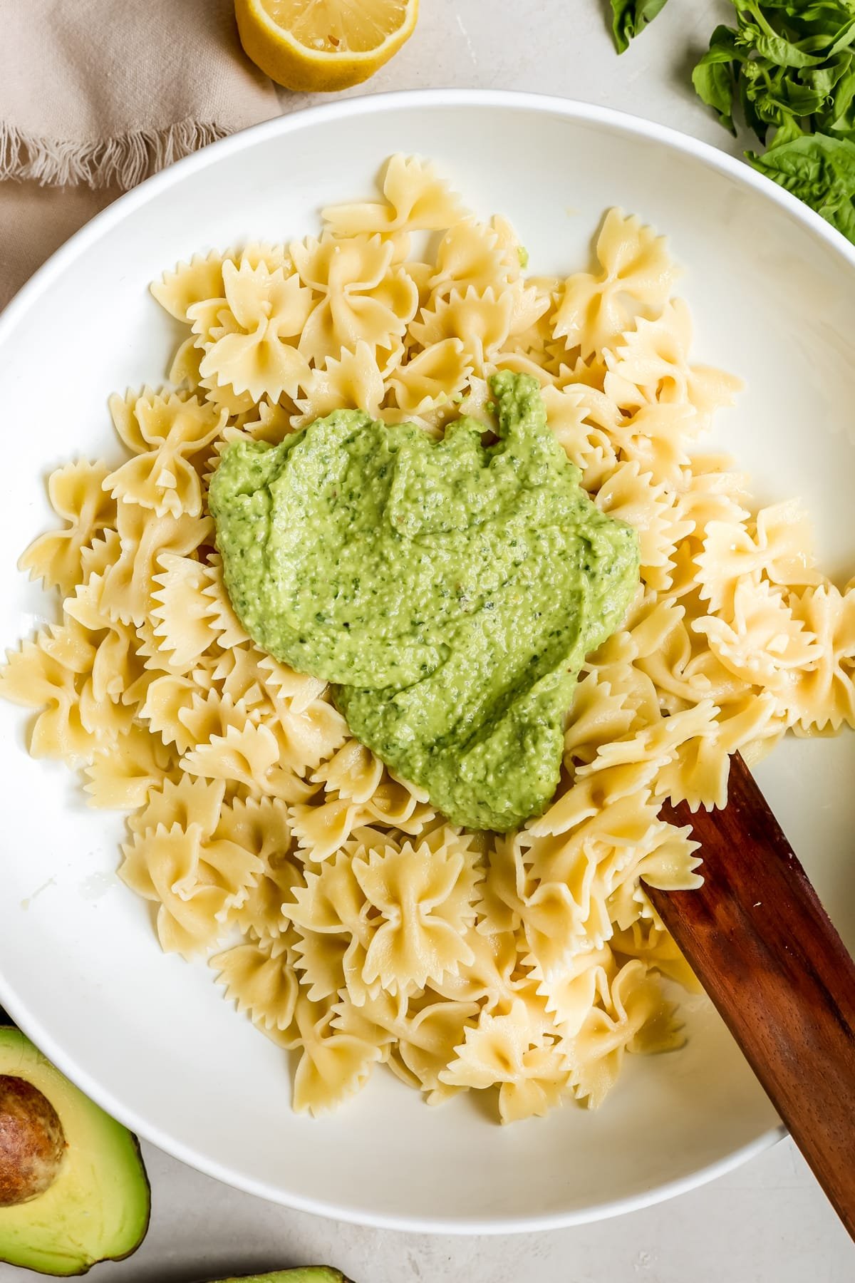 pasta in a white bowl with pesto on top. 