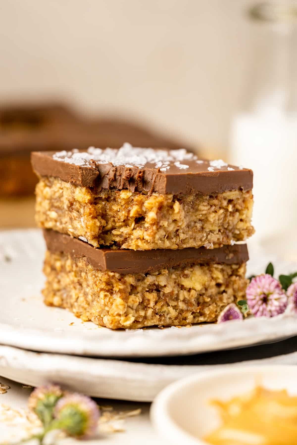breakfast bars stacked on top of each other with chocolate and flaky sea salt on top. 