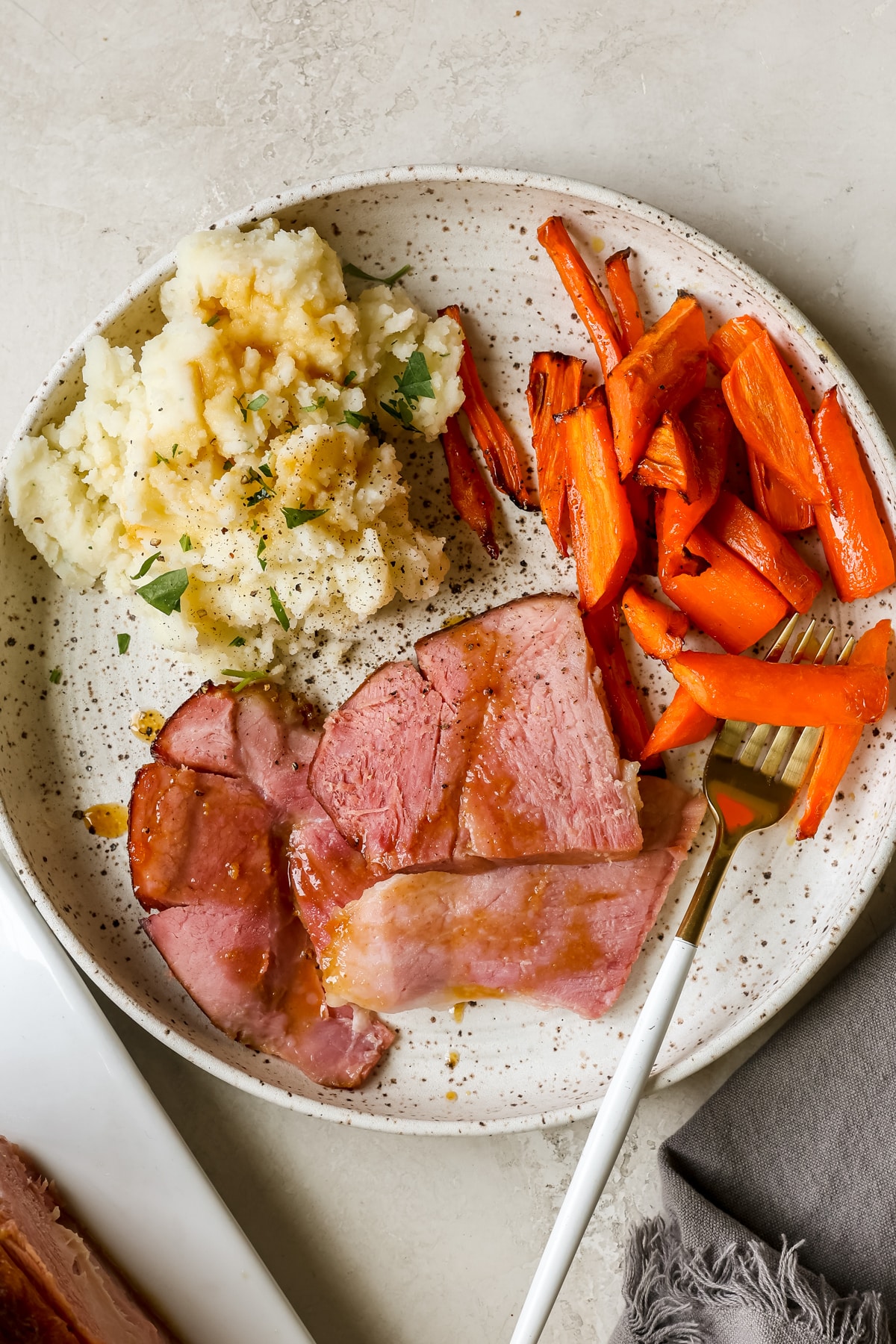 ham, carrots and mashed potatoes on a speckled white plate. 