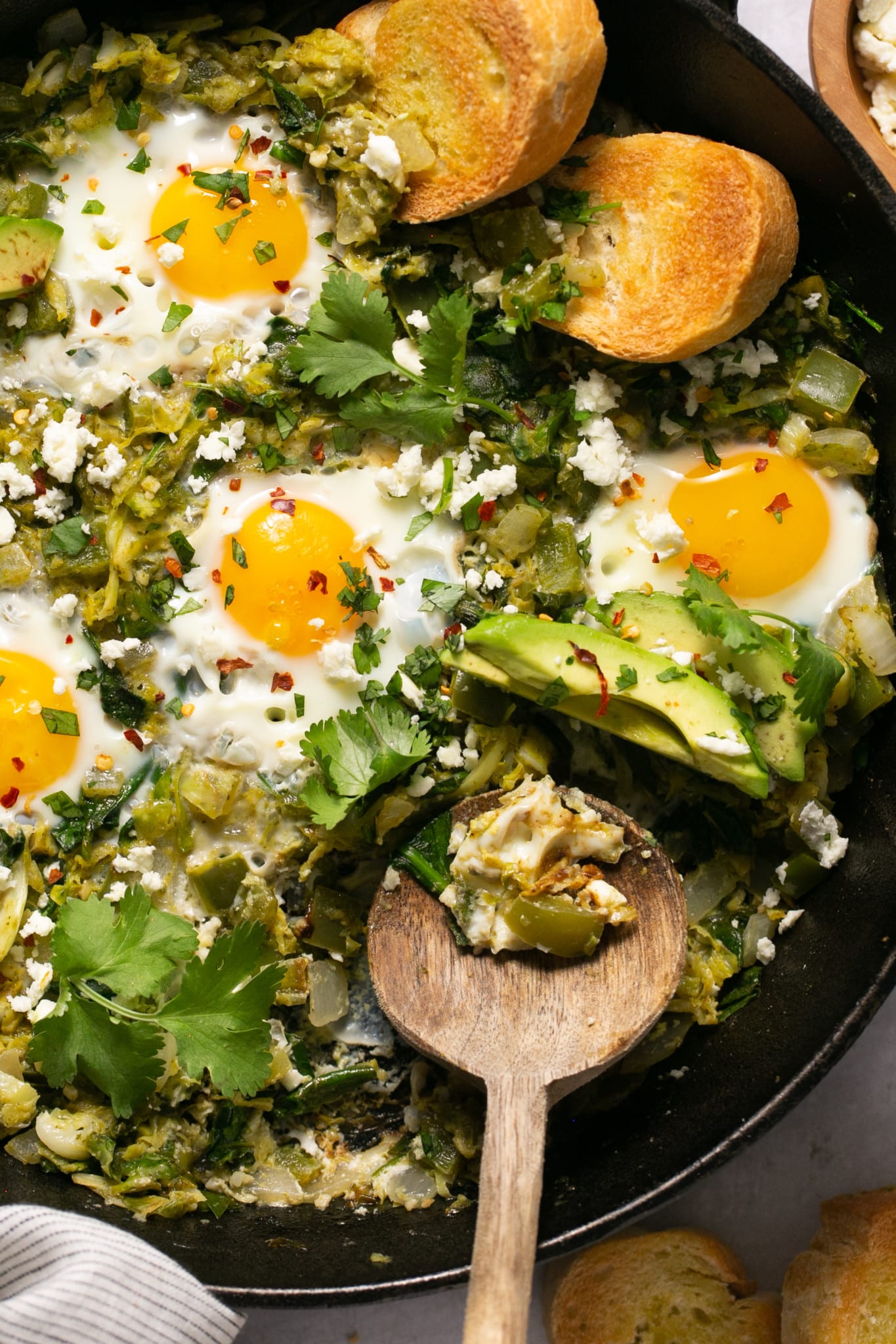 eggs in a skillet with veggies and avocado.