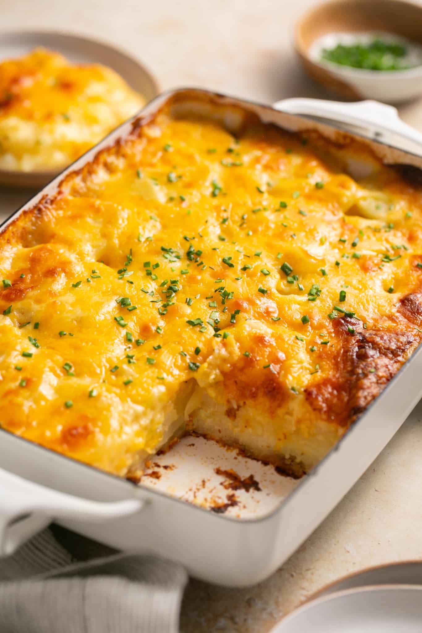 scalloped potatoes in a casserole dish garnished with chives. 